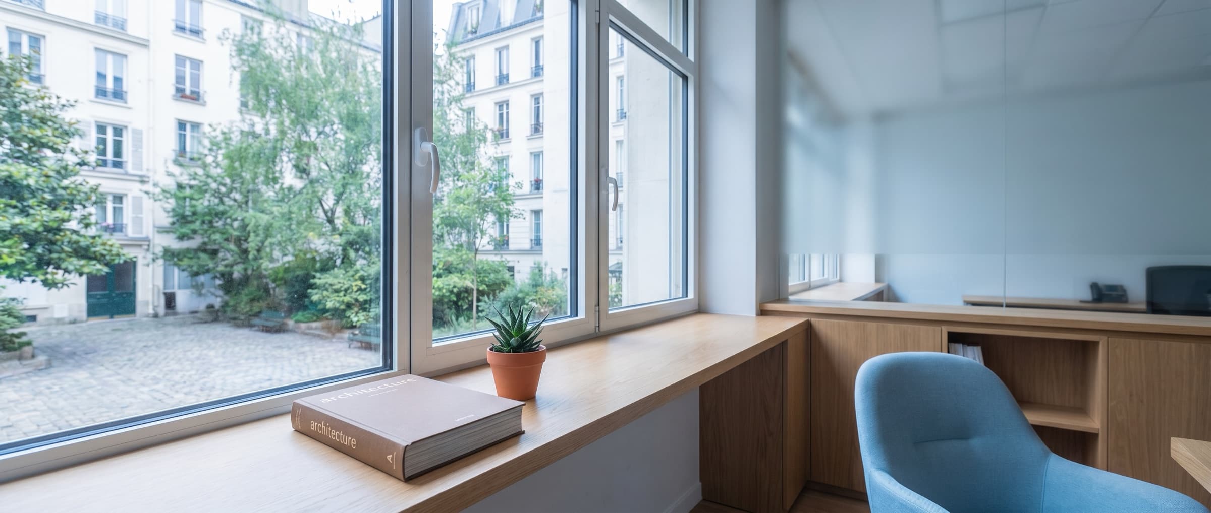 Vue par la fenêtre d'un bureau parisien sur cour résidentielle.